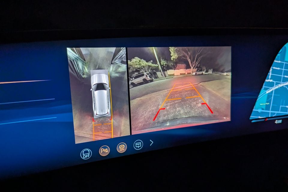 In-car display showing a 360-degree surround-view camera and reversing camera with parking guidelines overlaid, in a 2026 Cadillac VISTIQ at night