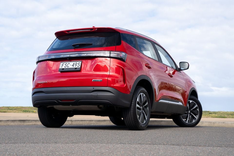 Red Chery Tiggo 4 viewed from the rear three-quarter angle, with its tailgate, wheels and side mirror visible.