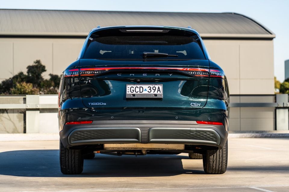 Rear view of a dark green Chery Tiggo 9 CS·H SUV parked in an outdoor area with a building in the background