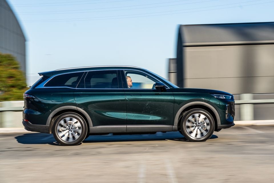 A dark green Chery Tiggo 9 SUV seen from the side while driving on a road