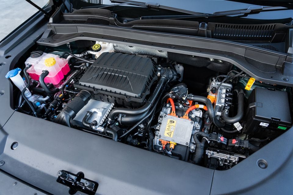 The hybrid engine bay of a 2026 Chery Tiggo 9 Super Hybrid, showing the petrol engine alongside orange high-voltage hybrid components and fluid reservoirs