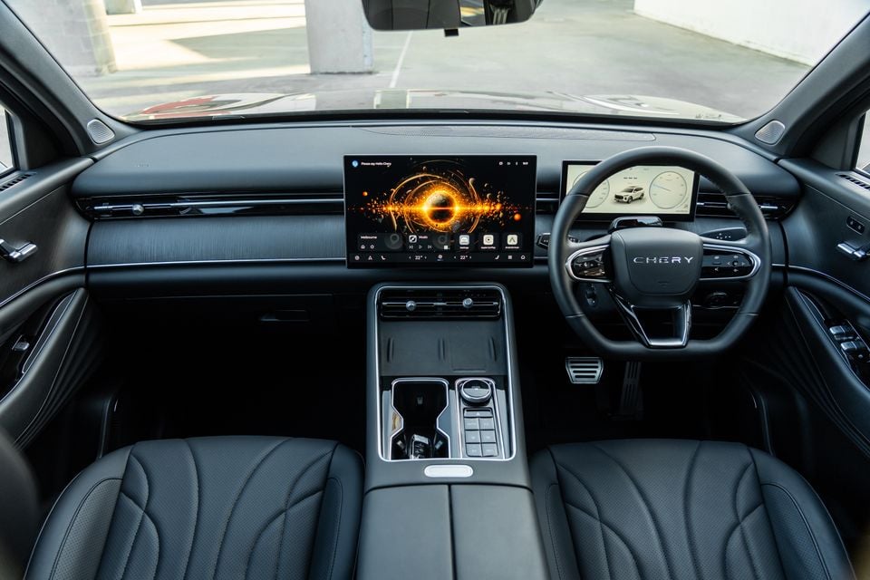 Interior of a Chery Tiggo 9 showing the dashboard, large central touchscreen infotainment display, digital instrument cluster, steering wheel, and centre console with dark leather seats