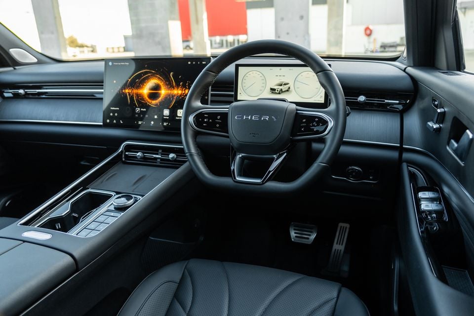 Interior of a Chery Tiggo 9 showing the steering wheel, large central touchscreen infotainment display, and digital instrument cluster from the driver's side