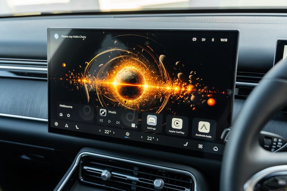 The infotainment touchscreen in a Chery Tiggo 9 Super Hybrid showing the home screen with music controls, Apple CarPlay, Android Auto, and climate settings