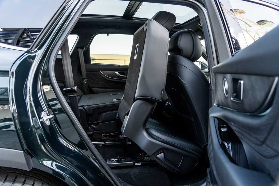 Interior view of a 2026 Chery Tiggo 9 SUV showing a folded second-row seat with the rear door open, revealing the third-row seating area and black leather upholstery