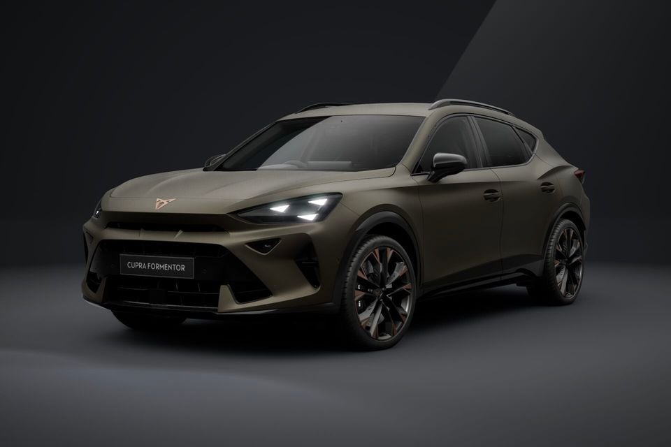 A Cupra Formentor SUV in a matte bronze finish, seen from a front three-quarter angle against a dark studio background.