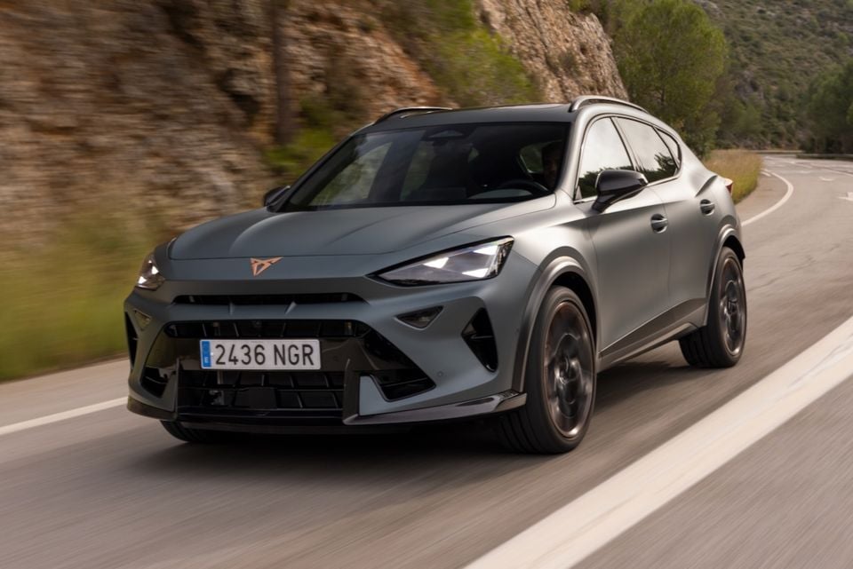 A grey Cupra Formentor VZ5 SUV driving on a winding mountain road, seen from the front-side