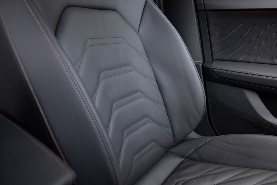 Dark grey leather rear seat of the 2026 Cupra Formentor VZe PHEV, showing geometric stitching detail and contrast copper stitching on the seatbelt trim