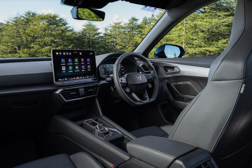 Interior of a Cupra Formentor VZe PHEV showing the dashboard, large touchscreen infotainment system, Cupra-branded steering wheel, and front seats with grey upholstery