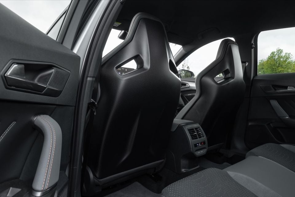 Rear view of the carbon fibre-backed bucket seats inside a 2026 CUPRA Formentor VZX, showing rear passenger space, door trim with orange stitching, and rear climate vents