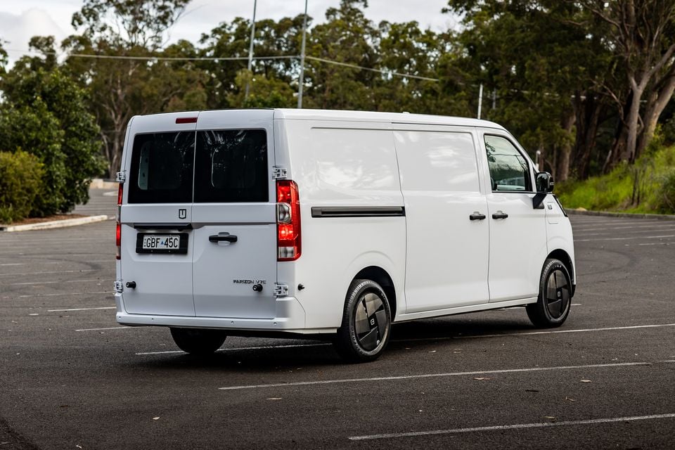A white 2026 Farizon V7E electric van seen from the rear three-quarter angle in a car park, surrounded by trees