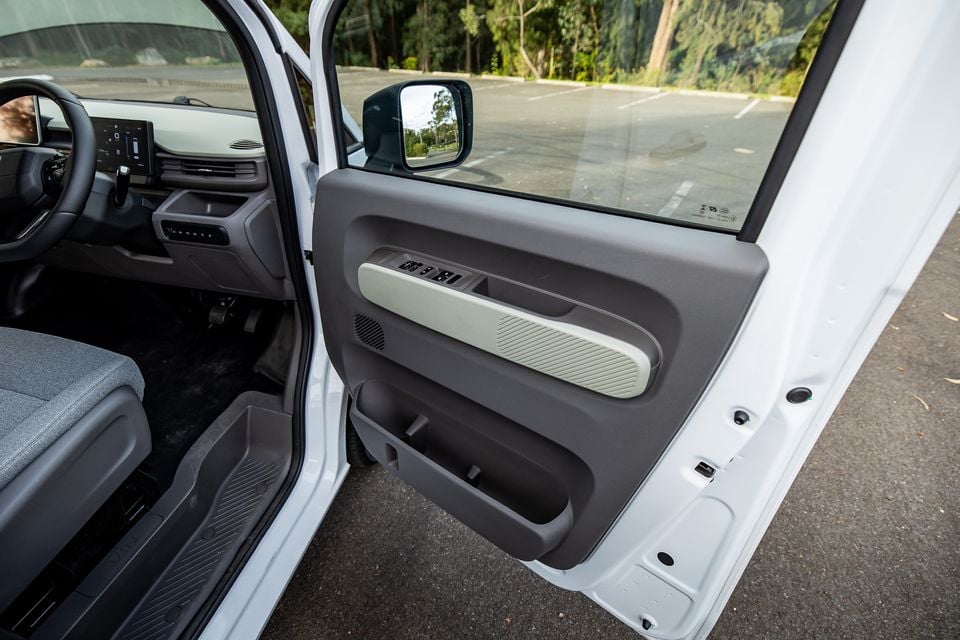Interior driver's door panel of a white 2026 Farizon V7E, showing window controls, door speaker and side mirror