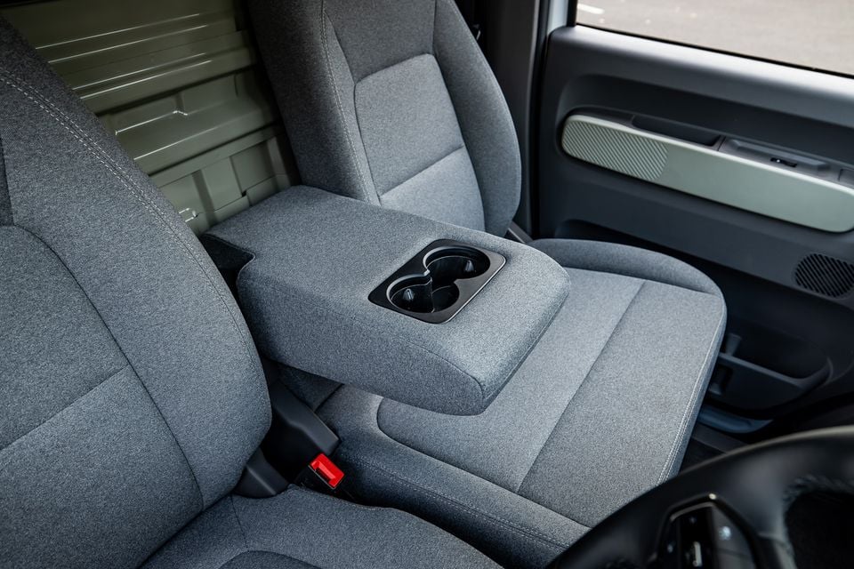 Front row cabin of the 2026 Farizon V7E showing grey fabric front seats with a centre armrest and dual cupholders