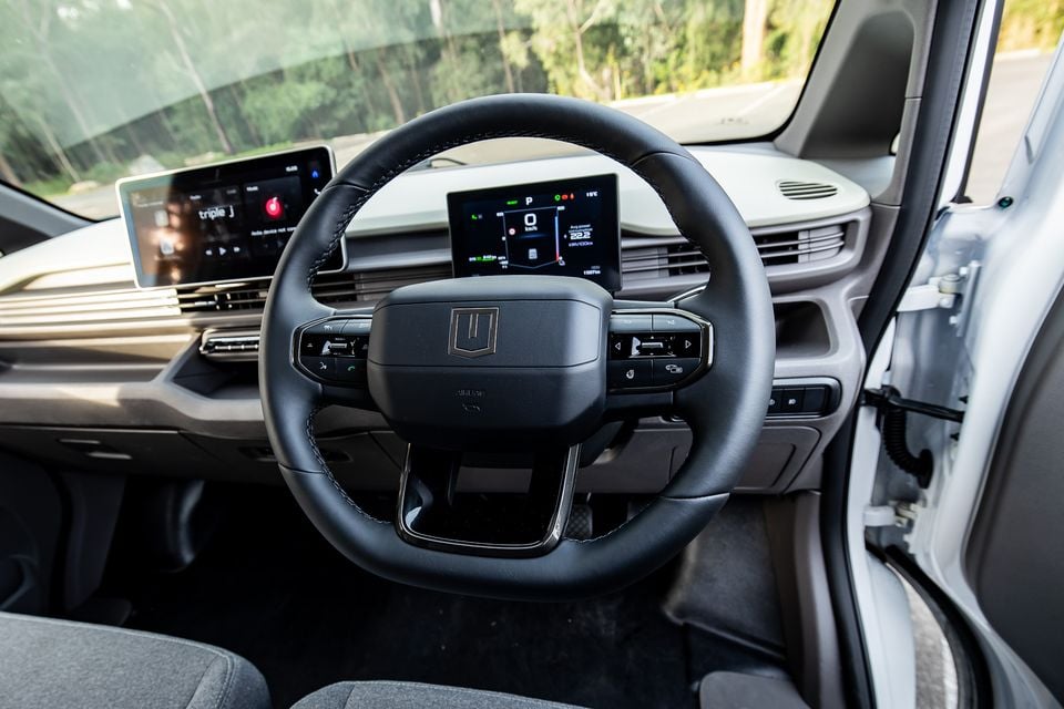 Interior view of a 2026 Farizon V7E showing the steering wheel, digital instrument cluster, and infotainment touchscreen displaying Triple J radio