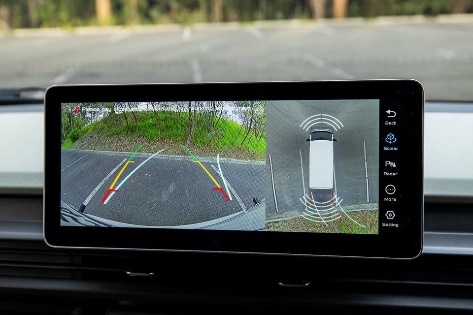 A car's infotainment screen displaying a reversing camera view with parking guidelines and a bird's-eye surround-view camera display