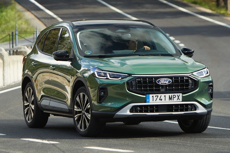 A green 2026 Ford Kuga SUV driving on a road, seen from the front at a slight angle