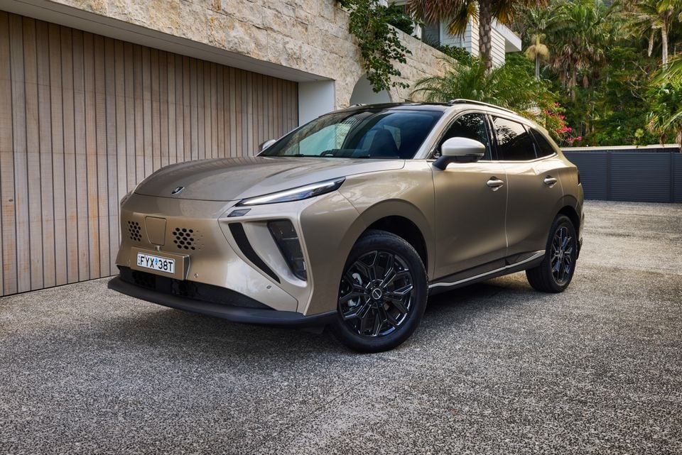 A gold/tan 2026 Forthing Taikon 5 SUV parked on a driveway in front of a garage, seen from the front-left angle