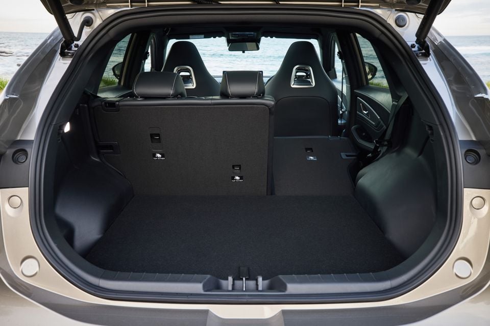 Empty boot of a Forthing Taikon 5 SUV with the tailgate open, showing carpeted cargo floor, top-tether anchor points, and sporty black seats visible through the cabin