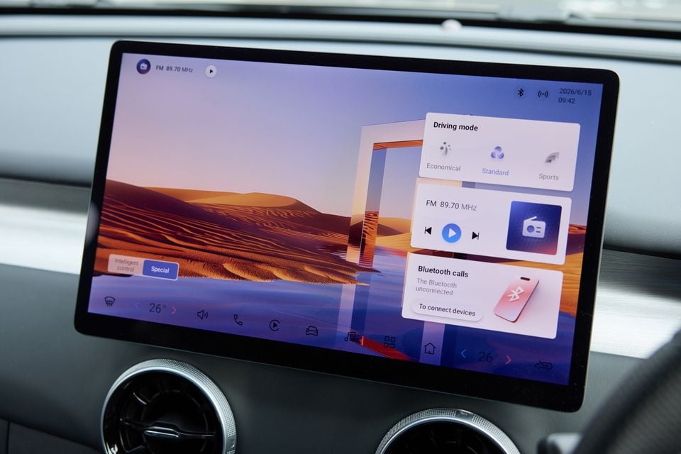 The touchscreen infotainment display inside a 2026 Forthing Taikon 5, showing driving mode, FM radio, and Bluetooth settings panels over a desert wallpaper.