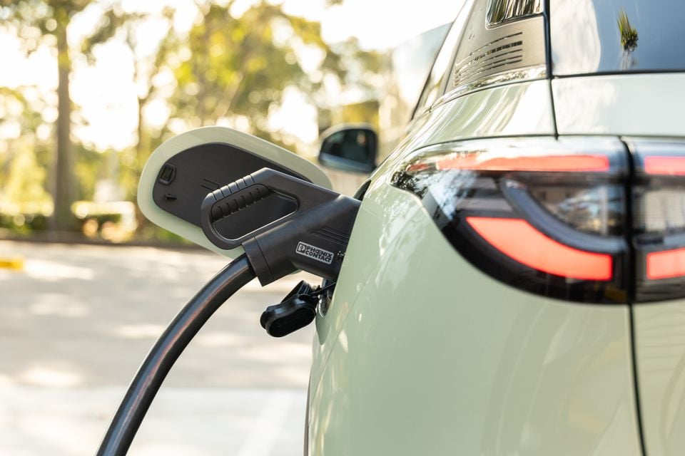 A Phoenix Contact EV charging cable plugged into the side charge port of a light green electric SUV, with the rear tail light visible in the background