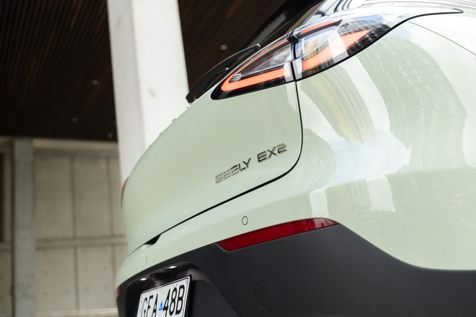 Close-up of the rear of a light green Geely EX2, showing the taillight and model badge