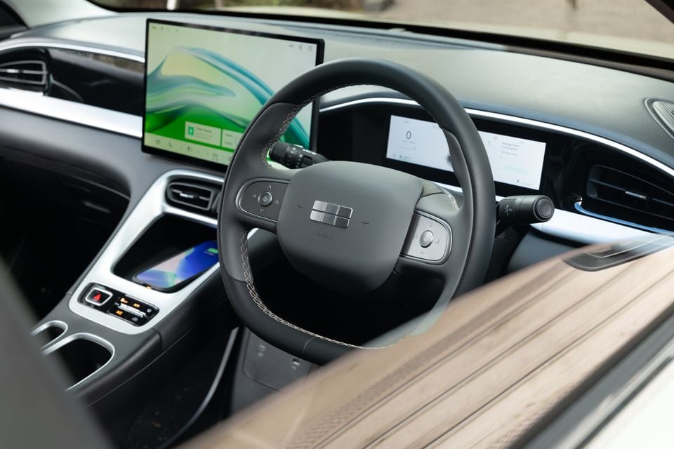 Interior of the 2026 Geely EX2 Inspire showing the steering wheel, large central touchscreen infotainment display, digital instrument cluster, and centre console with wireless charging pad