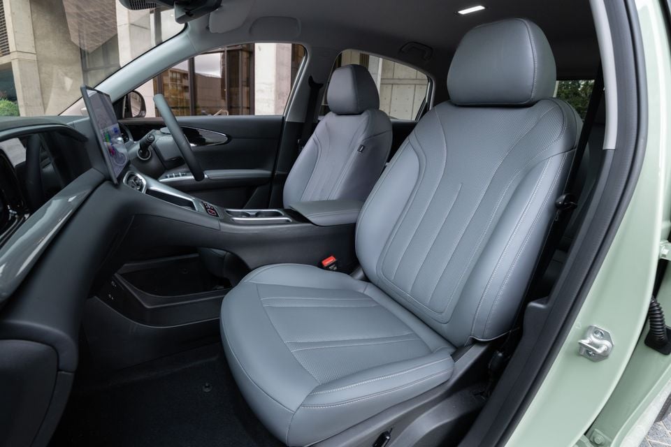 Grey leather front seats of a 2026 Geely EX2 Inspire, viewed from the open passenger door, with the centre console and touchscreen infotainment system visible in the background.