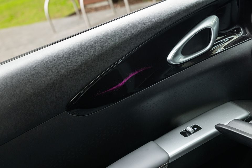 Interior door panel of the 2026 Geely EX2 Inspire, showing a black door card with ambient purple lighting strip and silver door handle
