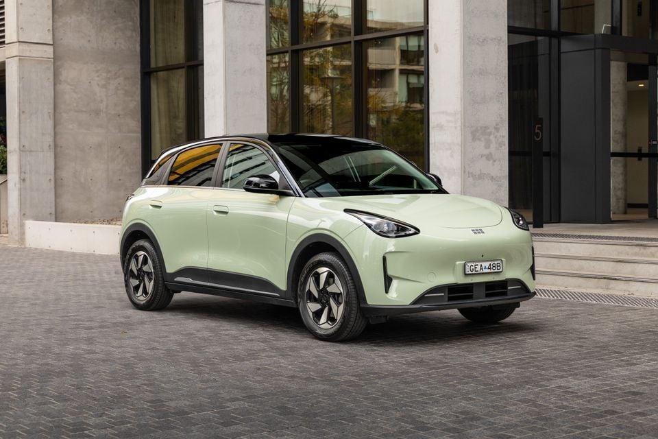 A light green 2026 Geely EX2 Inspire small SUV parked outside a modern building, seen from the front-side angle