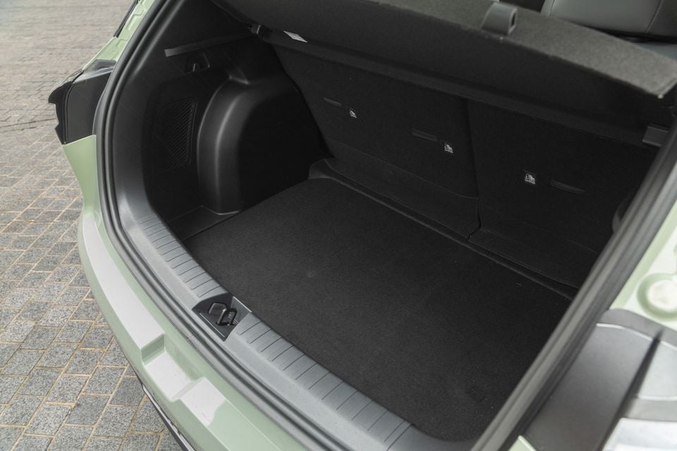 The open boot of a light green 2026 Geely EX2, showing a carpeted load floor and rear seat fold-down levers
