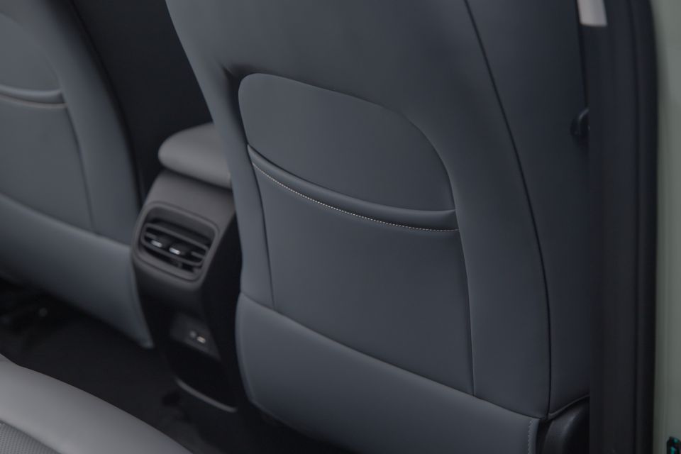 Close-up of the dark grey leather rear seat back with a seat pocket and rear air vents visible in a car interior