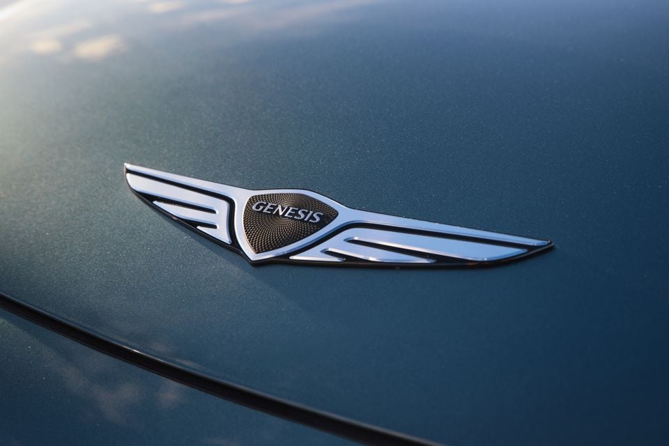 Close-up of the Genesis winged badge on the bonnet of a blue Genesis GV60