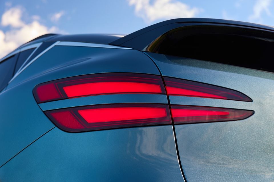 Close-up of the illuminated tail-light on a blue 2026 Genesis GV60, seen from the rear quarter.