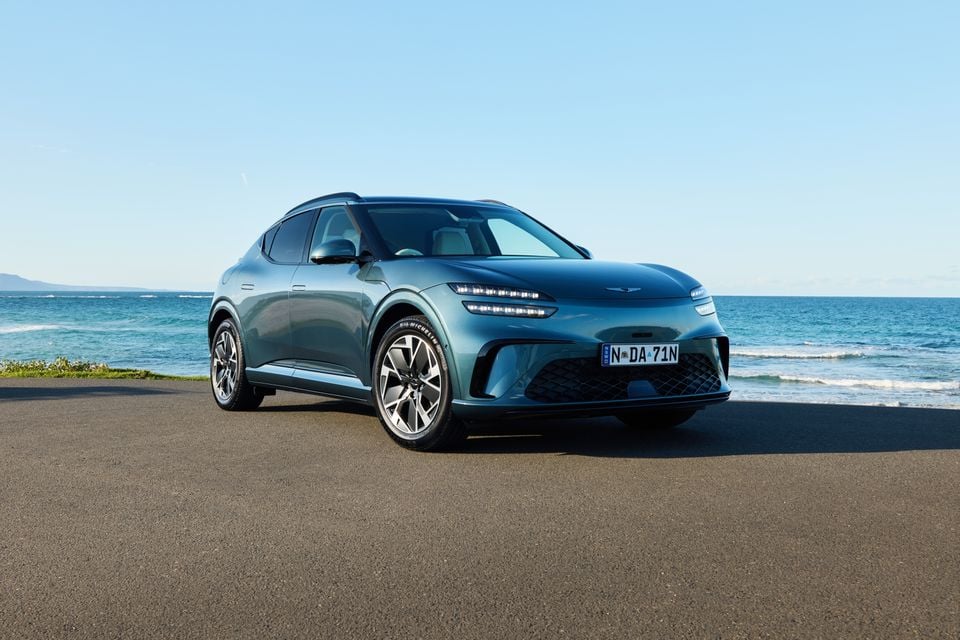 A teal 2026 Genesis GV60 SUV parked near the ocean, seen from the front-left side