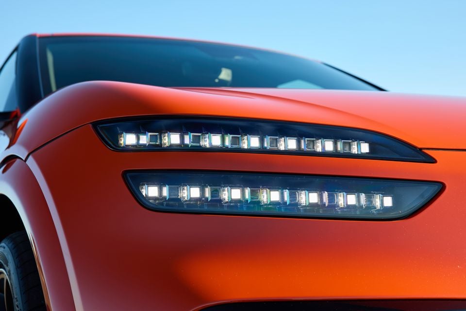 Close-up of the LED headlights on an orange 2026 Genesis GV60 Magma