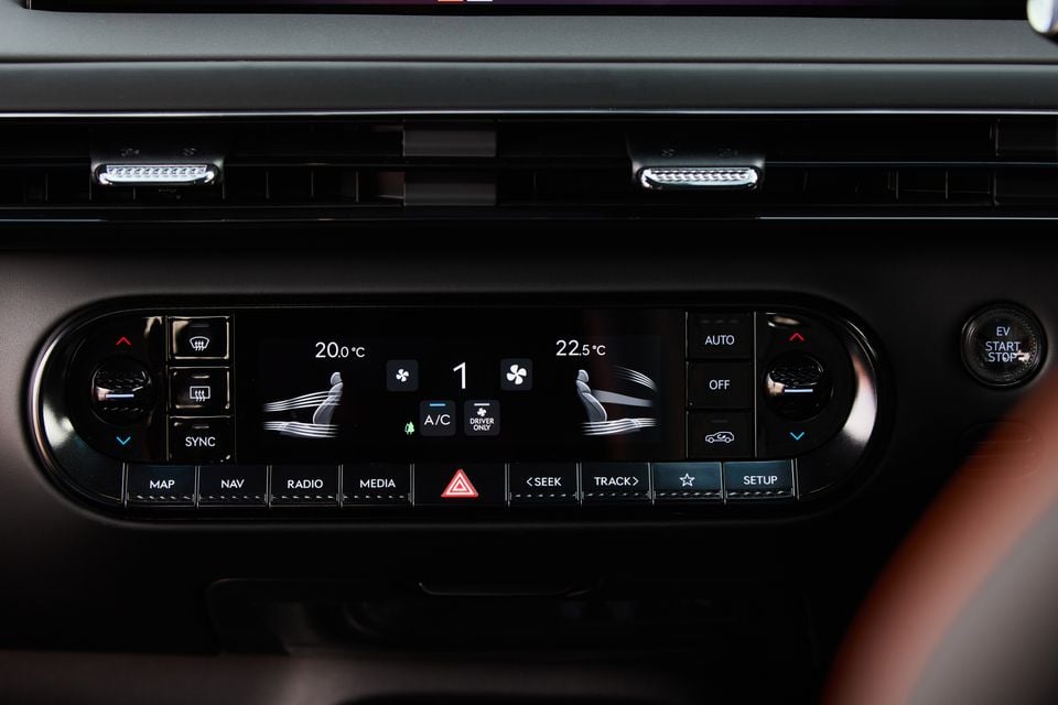 Close-up of the climate control and infotainment panel in a 2026 Genesis GV60 Magma, showing dual-zone temperature settings and media controls