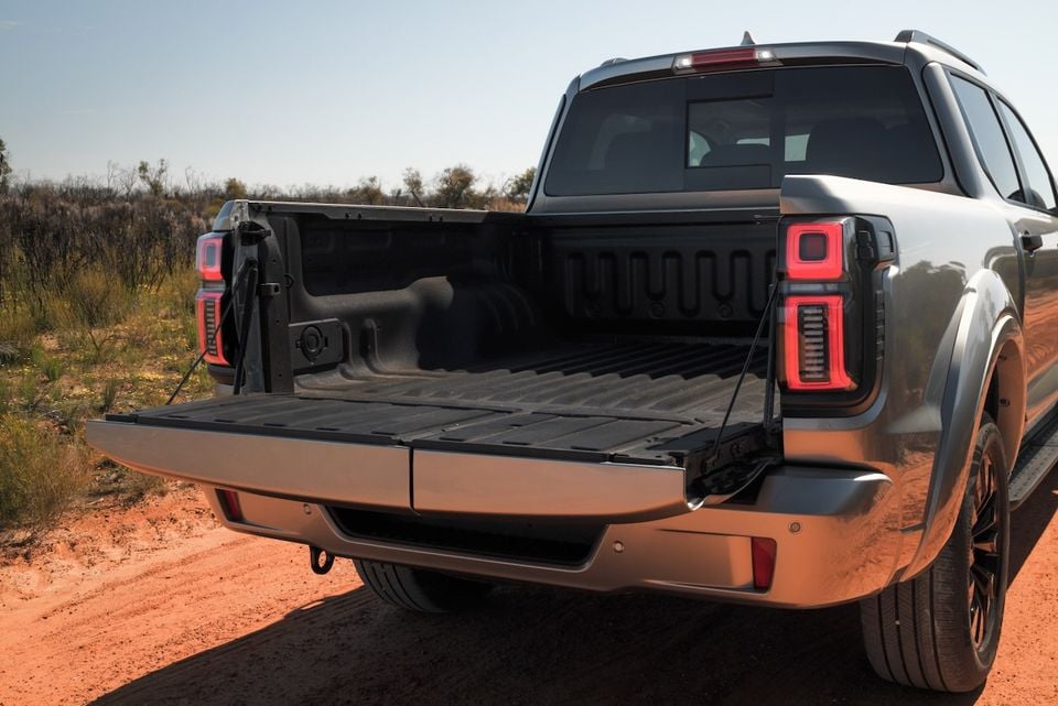 A silver 2026 GWM Cannon Alpha dual-cab ute with its tailgate down, showing the tray bed, parked on a red dirt road.