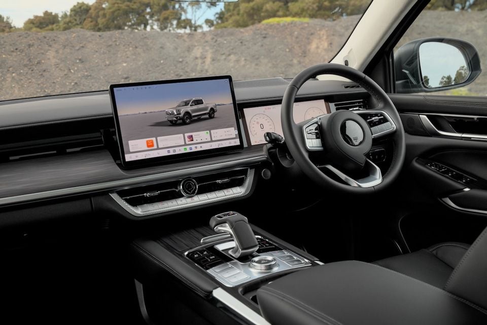 The black leather interior of a 2026 GWM Cannon Alpha ute, showing the steering wheel, dual screens, and centre console.