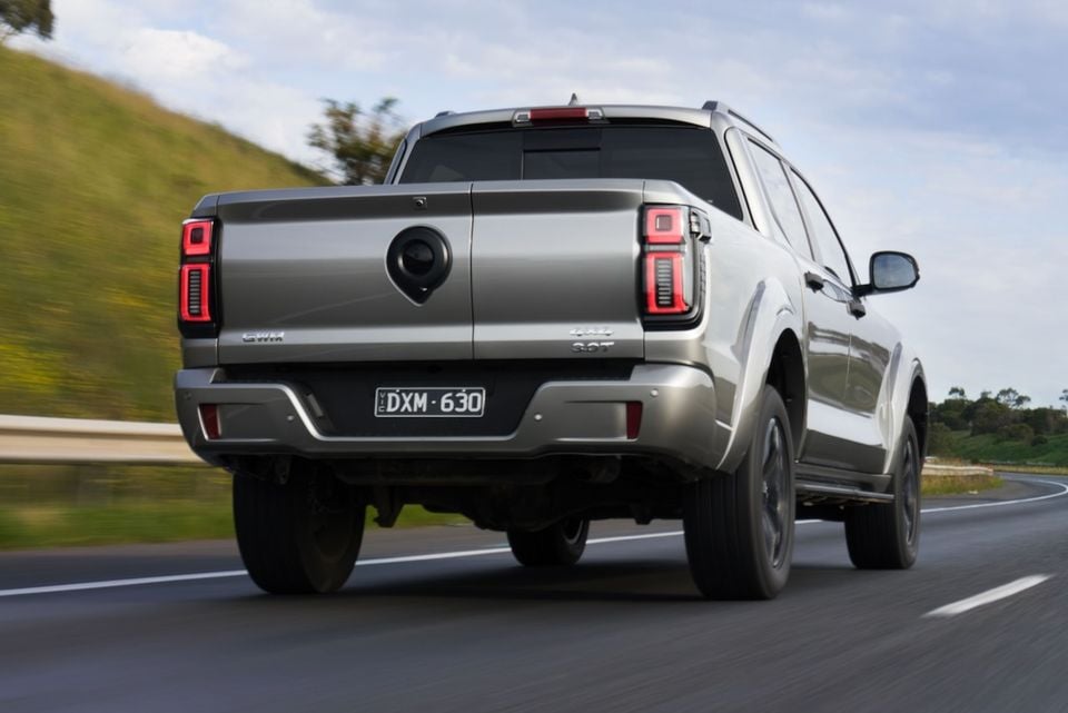 A silver GWM Cannon Alpha dual-cab ute driving on a highway, seen from the rear