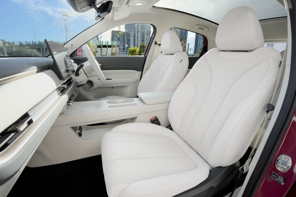 White leather front seats and dashboard interior of a 2026 GWM ORA 5 SUV, viewed from the passenger-side door