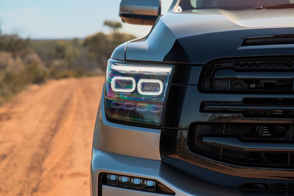 Close-up view of the headlight and grille on a silver 2026 GWM Tank 500 parked on a dirt road