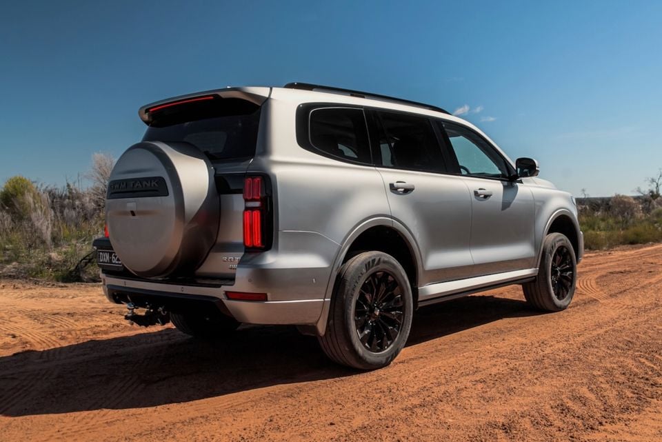 A silver 2026 GWM Tank 500 SUV with a rear-mounted spare wheel, seen from the rear quarter on a dirt track