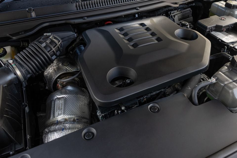 Close-up view of the engine bay of a 2026 GWM Tank 500, showing the engine cover, exhaust manifold heat shield and battery.