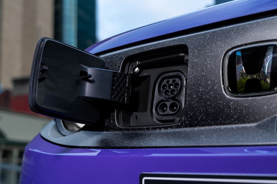 Close-up of the open charging port on a purple 2026 Honda Super One electric car, with the headlight visible to the right.