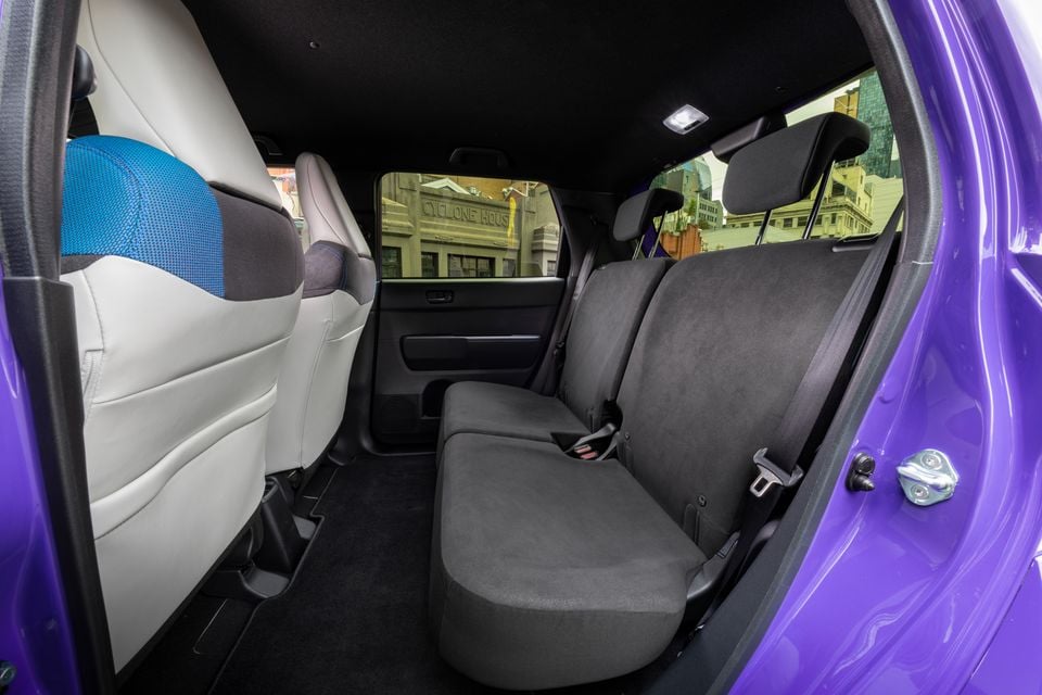 The rear seats of a purple 2026 Honda Super One, viewed through the open rear door showing black upholstery.