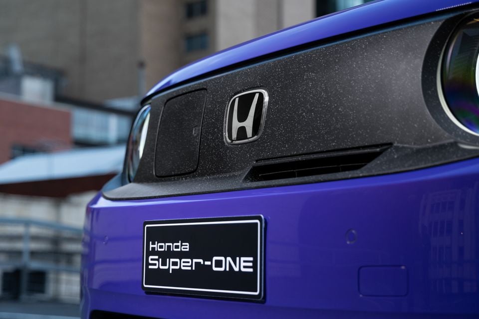 Close-up of the front badge and headlight on a blue Honda Super-ONE, with a "Honda Super-ONE" plate below