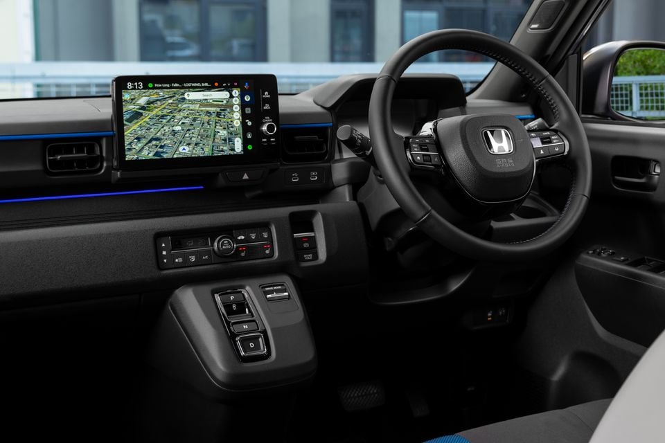 The interior of a 2026 Honda Super One showing the steering wheel, digital touchscreen with map display, and gear selector buttons