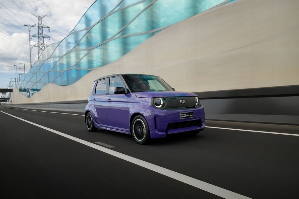 A purple 2026 Honda Super-ONE electric hatchback driving on a highway, seen from the front quarter