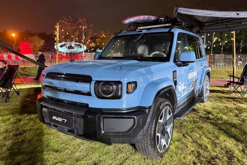Blue iCaur V27 overseas display car, identified by its V27 plate, with roof-mounted outdoor accessories and an extended awning; not a V25 or confirmed Australian equipment specification.