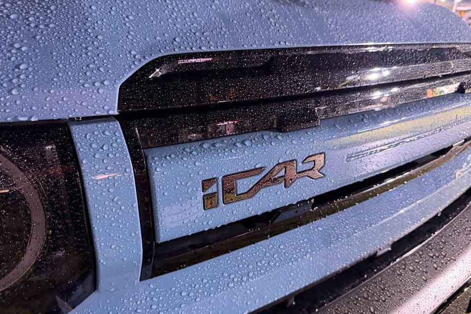 Close-up of the iCAR badge and grille on the blue overseas iCaur V27 display car; not the V25 discussed in the range comparison.